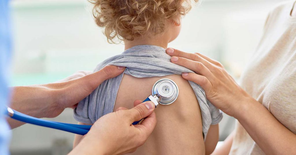 Criança em avaliação com estetoscópio durante atendimento pediátrico
